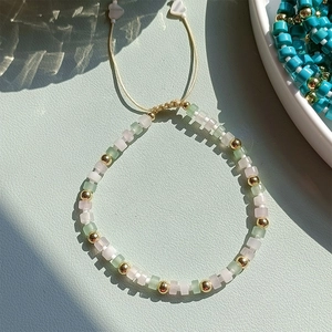 Detailed macro view of mint green and pink square beaded bracelet with gold accents