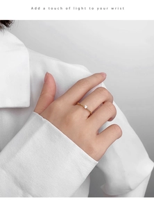 Close-up of minimalist gold plated ring with a brilliant round zircon on finger