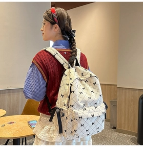 Detail of cream corduroy backpack with black ribbon bows and quilted pattern on model