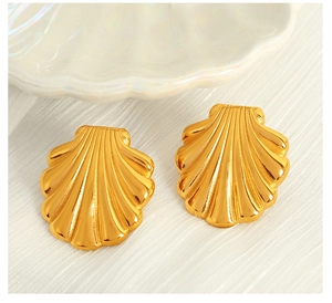 Detailed macro view of gold-plated shell earrings with polished fan-shaped texture