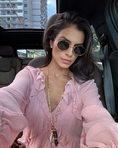 Gros plan d'un collier doré superposé porté avec une robe en mousseline rose à volants