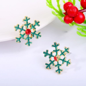 Macro detail of snowflake stud earring with green enamel, red gem and golden finish