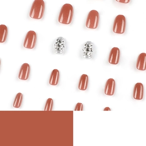 Terracotta orange press-on nails with silver glitter and rhinestone accents on white background