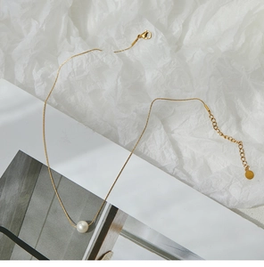 Detail of single pearl necklace featuring an 18K gold-plated chain and lobster clasp