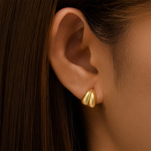 Detail of matte gold geometric crossover stud earrings showing brushed metal texture