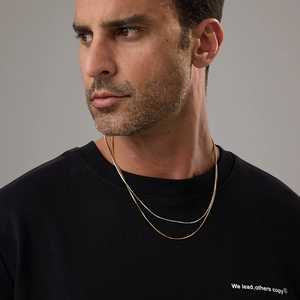 Detail of layered gold and silver snake chains on a black shirt for a modern look