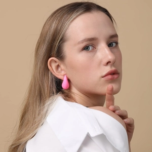 Close-up of pink teardrop earrings on a model with a minimalist beige background