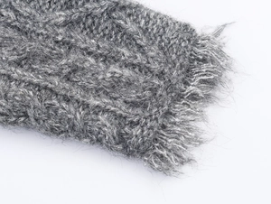 Dettaglio macro del cardigan grigio a maglia a trecce con trama morbida e frange