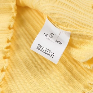 Détail d'un ensemble en tricot jaune avec étiquette taille S et texture 100% polyester