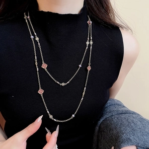 Detail of double-layer gold chain with pink clover pendants and matte purple beads