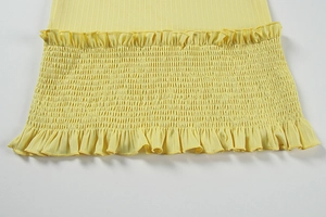 Détail d'une robe jaune côtelée avec taille élastique froncée et bords à volants fins