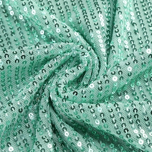 Macro detail of mint green sequin fabric with high density embroidery and shimmering texture