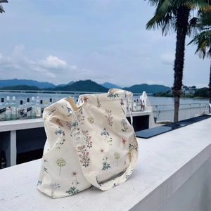 Detail of floral canvas tote bag showing wide printed strap and interior brand label