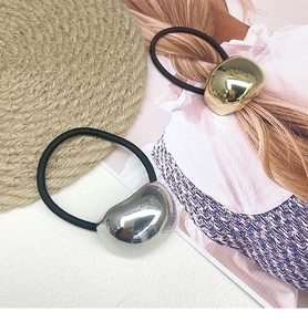 Detailed close-up of bean-shaped gold and silver hair ties with polished mirror finish