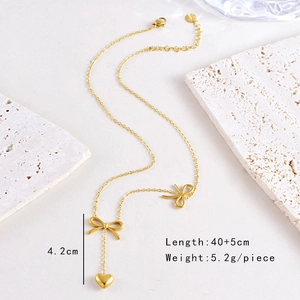 Detailed macro of golden bow and heart pendant necklace on textured stone background