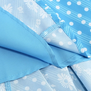 Macro detail of blue floral dress fabric with white daisies, polka dots and fine stitching