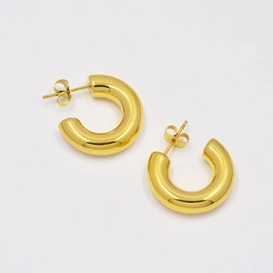 Macro detail of high-polished golden C-shaped hollow hoop earrings in titanium steel