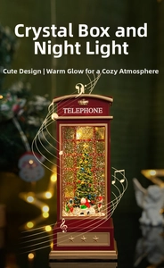 Close-up of a red British telephone booth music box with an internal Christmas tree and snow
