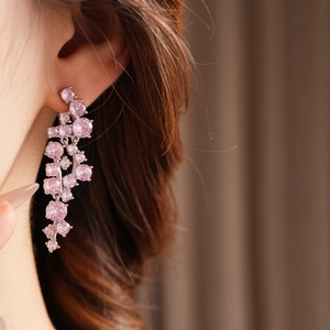 Detail of elegant silver drop earring with shimmering pink zircons on model ear