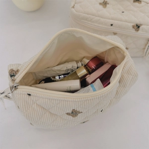 Detail of quilted corduroy makeup bag with brown bear embroidery and storage capacity