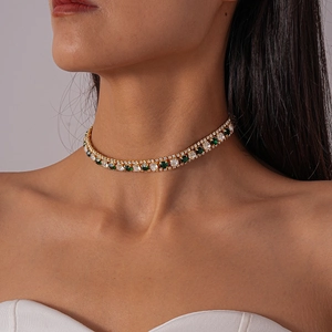 Macro detail of gold necklace with green and clear square-cut zircon stones on model