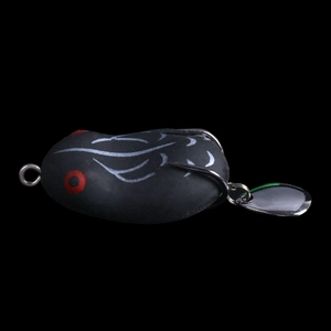 Detail shot of a black frog lure with red eyes, sharp double hooks, and metal spinner tail