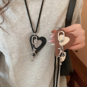 Detail of leather heart puppy pendant with metal accents on a long woven necklace