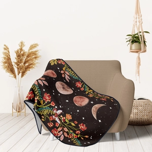 Bohemian black flannel blanket with lunar phases and floral patterns on a beige chair