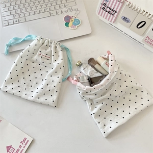 Detailed close-up of polka dot drawstring bags storing cosmetics with colorful ribbons