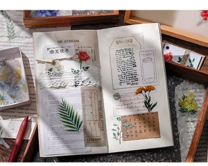 Close-up of vintage scrapbook with floral stickers, lace, and dried flower decorations