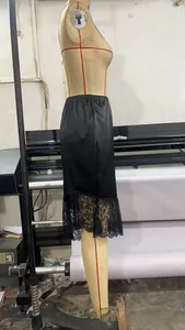 Close-up of the delicate floral lace hem on a smooth black satin skirt detail