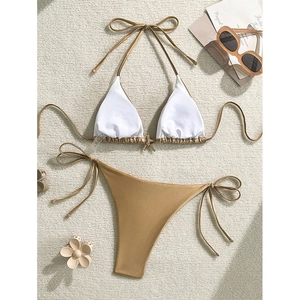 Bikini de dos piezas blanco y dorado con colgante de estrella de mar sobre alfombra blanca