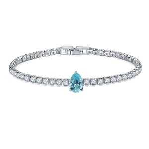 Close-up of silver tennis bracelet featuring a pear-shaped light blue gemstone and zircons