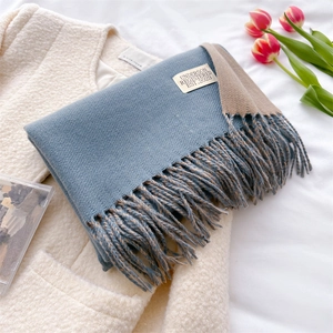 Detail of blue and grey cashmere scarf with fringe and label on white wool coat