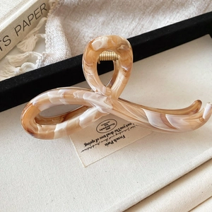 Detailed amber marble textured hair claw clip with golden metal spring on canvas base