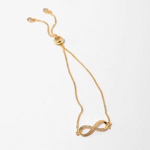 Detailed view of gold infinity bracelet with zircon pavé and adjustable heart charms