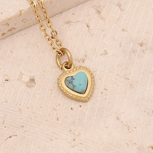 Macro view of heart-shaped turquoise pendant with beaded gold frame on stone