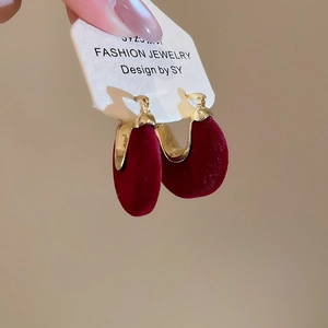 Close-up of deep red velvet U-shaped earrings with a polished gold-tone metal frame