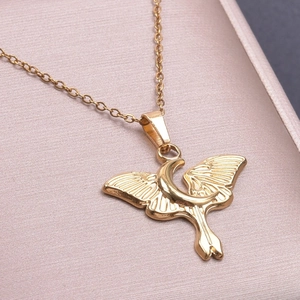Macro shot of 18k gold butterfly and moon pendant necklace on pink satin background