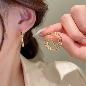 Elegant gold hoop earrings with CD logo charm on a model for a luxury fashion look