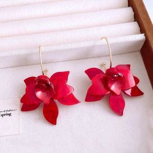 Gros plan de boucles d'oreilles fleurs en résine rouge avec crochets dorés en boîte