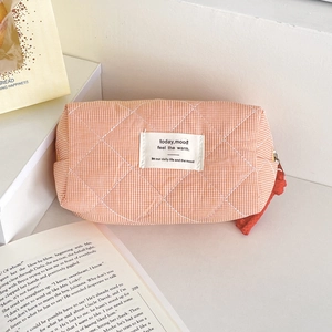 Close-up of quilted plaid makeup bag with vintage orange checkerboard and logo tag