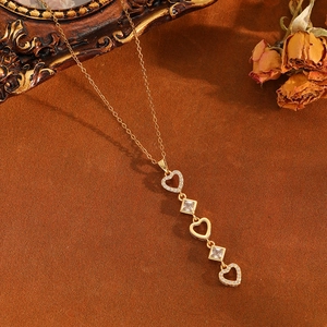 Détail macro d'un collier pendentif cœur doré avec strass et pierres précieuses carrées