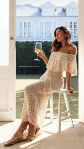 Dettaglio del vestito lungo beige all'uncinetto con motivi traforati e nappe in vita