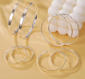 Detailed set of four polished silver hoop earrings in varying sizes on aesthetic background