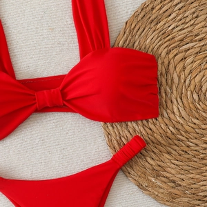 Bikini rouge deux pièces avec haut bandeau à nœud et culotte volantée sur fond blanc