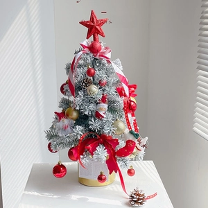 Mini snow flocked Christmas tree with red gold ornaments and a steady golden base