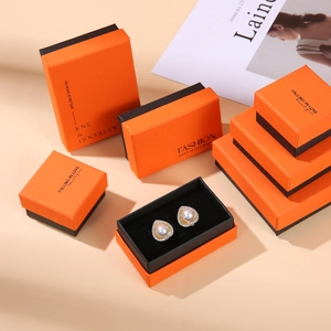 Detailed view of orange and black drawer jewelry boxes with heart pearl earrings