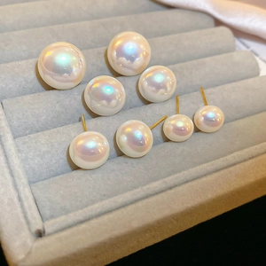 Detailed view of various sizes of mermaid pearl studs on a luxury velvet display box