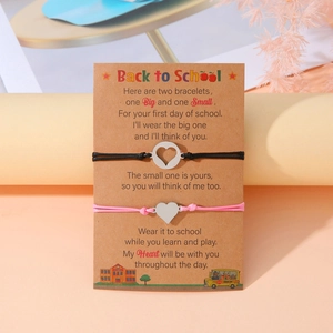Dettaglio di braccialetti a cuore rosa e nero su carta Back to School con poesia e arte scuola